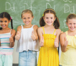 Smiling kids showing thumbs up in classroom